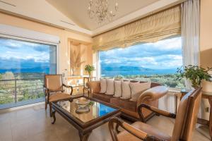 卡拉莫斯Luxe Villa Amfiario in Attica region, pool & breathtaking views!的带沙发和椅子的客厅以及大窗户。