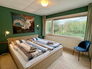 海滨诺德韦克Beach House Wantveld Noordwijk aan Zee的一间卧室配有一张带椅子的床和一扇窗户