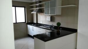库里提巴Apartamento Central Curitiba的厨房配有白色橱柜和黑色台面