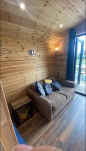 邓加文The Peregrine - 2 Person Luxury Glamping Cabin的木墙的房间里一张沙发