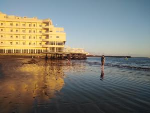 厄尔梅达诺Alquilaencanarias El Faro Beach的站在海滩上,靠近一座大建筑的人