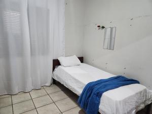 图托亚Mini Hostel的小房间,床上挂着蓝色毯子