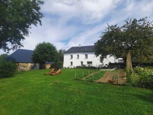 TrocheGîte dans ancien corps de ferme à 5mn de Pompadour的院子内有两长椅的白色房子