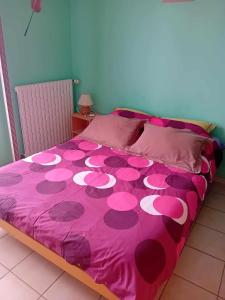 Le BaconLE PETIT VERMONDOIS的一张带粉红色床罩的床,上面有粉红色的花朵