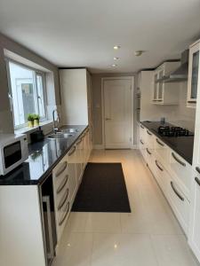 布伦特福德Brentford Guest Rooms的一间大厨房,配有白色橱柜和黑色台面