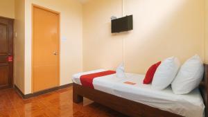 达沃市RedDoorz at Casa Buena Dormitel Davao City的一间卧室配有一张带枕头的床和一台墙上的电视。