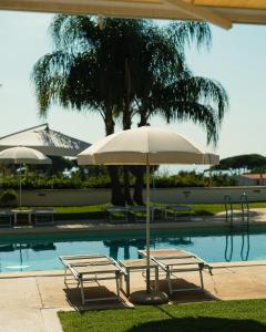 斯佩隆加格罗塔狄缇贝里欧酒店的游泳池旁的两把椅子和一把遮阳伞