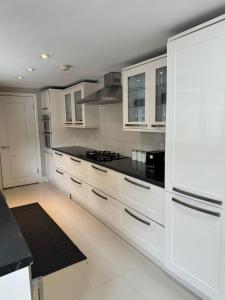 布伦特福德Brentford Guest Rooms的厨房配有白色橱柜和黑色台面