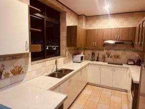 基加利AMORA APARTMENT的厨房配有白色橱柜、水槽和窗户。