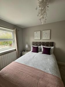 布伦特福德Brentford Guest Rooms的一间卧室配有一张带紫色枕头的大床