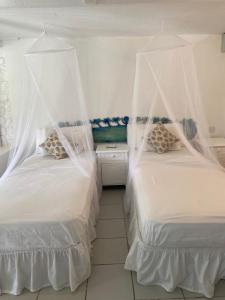 马里戈特湾Blue Bamboo cottage Marigot Bay.的一间卧室配有两张带蚊帐的床