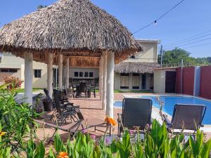 MarcelinoRancho Del Oso Tuerto的一个带游泳池、椅子和稻草小屋的度假村