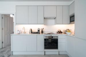 伦敦Niru Experience Royal Deluxe 4BD 2BA Apt的白色的厨房配有白色橱柜和洗碗机。