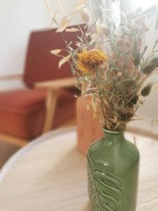 HorebekeB&B Lili's Tuin的绿花瓶,桌子上放着鲜花