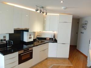 直布罗陀Urban Oasis at Luxurious Ocean Village的厨房配有白色橱柜和黑色台面
