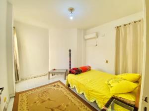 ‘Ezbet el-Ibrâshiفيلا in fayed的一间卧室配有黄色的床和地毯
