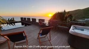 TábuaCastelo do Mar, Madeira的一个带两把椅子的甲板和日落时的海洋