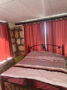 Ad DimnahAl-Karak Countryside and hotel的红色窗帘的房间的一张床位