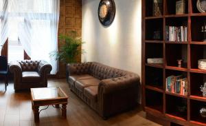 克拉科夫哥伦布酒店的客厅配有真皮沙发和书架