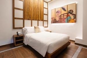 圣安德烈斯Prixma Hotel的卧室配有一张床,墙上挂有绘画作品