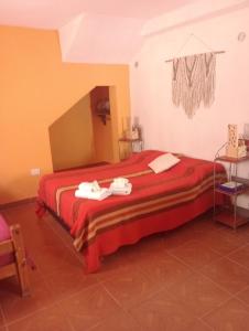 普尔马马尔卡Ipay Alojamiento Familiar的一间卧室配有红色的床和毛巾
