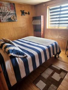科伊艾科Ruta Austral - Coyhaique的一间卧室配有一张带蓝白条纹毯子的床