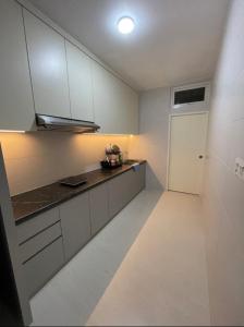 古晋J&SM Riverine resort homestay的厨房配有白色橱柜和白色地板