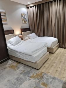 Sīdī Ḩamzahبيت الجود للأجنحة المفروشة的配有白色床单的酒店客房内的两张床