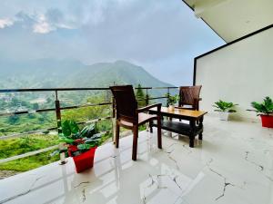 穆索里The Four Season Resort - Top Rated & Most Awarded Property in Mussoorie的阳台配有2把椅子和1张桌子,享有风景。