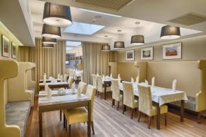 卡利什拉祖尔酒店、水疗及会议中心的餐厅设有白色的桌子和黄色的椅子
