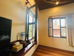 琅勃拉邦Villa Ban Pakham Hotel的客房设有2扇窗户和1张木桌。