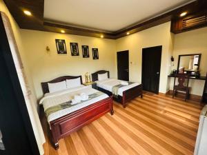 琅勃拉邦Villa Ban Pakham Hotel的一间卧室设有两张床,铺有木地板