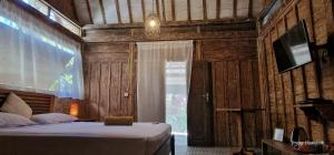 吉利特拉旺安Villas Light House - Eco-Traditional Joglo的一间卧室配有一张床和一台电视。