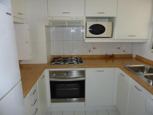 阿尔加罗沃圣阿方索维斯塔马尔公寓的厨房配有白色橱柜和炉灶烤箱。