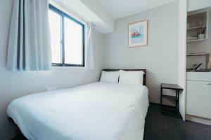 东京unito SHIODOME的卧室配有白色的床和窗户。