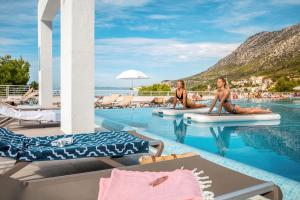 伊格拉恩TUI BLUE Adriatic Beach - All Inclusive - Adults Only的两名妇女坐在度假村的游泳池冲浪板上