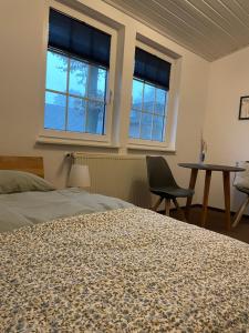 韦塞尔Landhaus am Loh的一间卧室配有一张床、一张桌子和两个窗户