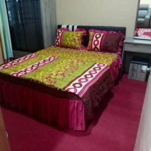 Kuala KeraiAqiza Home Kuala Krai的一间卧室配有一张带绿色和粉色毯子的床