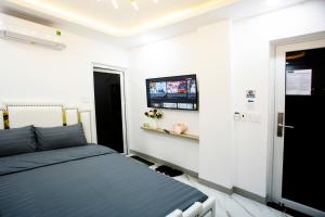 胡志明市Le Vu Hotel的卧室配有一张床,墙上配有电视。