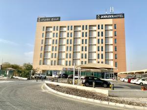 迪拜JOIN INN HOTEL Jebel Ali, Dubai - Formerly easyHotel Jebel Ali的一座大型建筑,前面有停车位