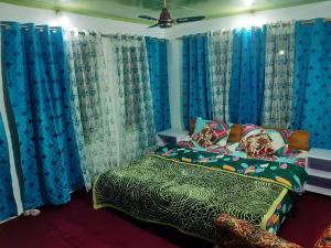 Bāgh ChandpuraRose Bowl Guest House Homestay的一间卧室配有蓝色窗帘和一张带被子的床