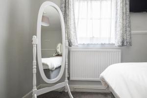 韦茅斯Gresham Guest House的卧室内的白色镜子,配有床