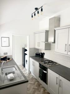 克利索普斯2 bedroomed house close to Cleethorpes seafront的白色的厨房设有水槽和炉灶。