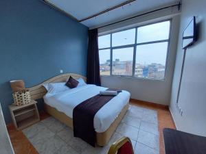 内罗毕Fahari Bliss Hotel的一间卧室设有一张床和一个大窗户