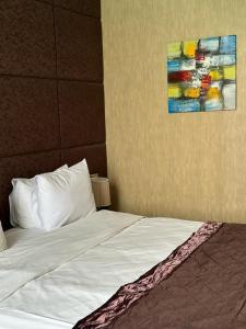 巴库Sherlock Hotel Baku的一张铺有白色床单的床和墙上的绘画