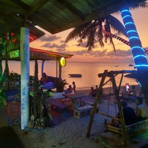 班泰双石旅馆的一群坐在海滩上的人,看着日落
