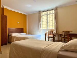 金马士Tropicana Hotel的酒店客房带两张床和一张桌子以及椅子。
