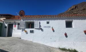 El JuncalCasa Rural LOS PINARES El Juncal de TEJEDA的白色的建筑,旁边标有标志