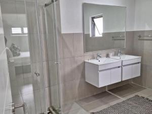 巴利托Simbithi Golf Estate Luxury Apartment的带淋浴、盥洗盆和镜子的浴室