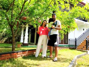 DaganapothahaSigiriya Cashew Palace Resort的男妇在房子前抱着婴儿